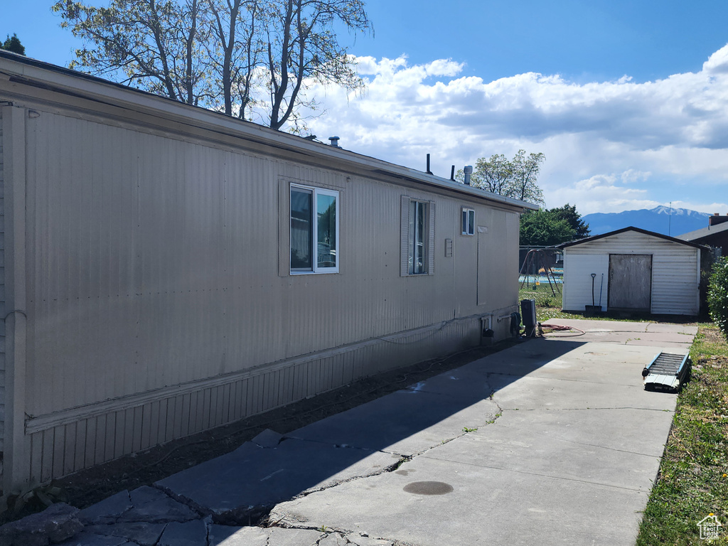View of side of home featuring a storage shed, an outdoor structure, and a patio area