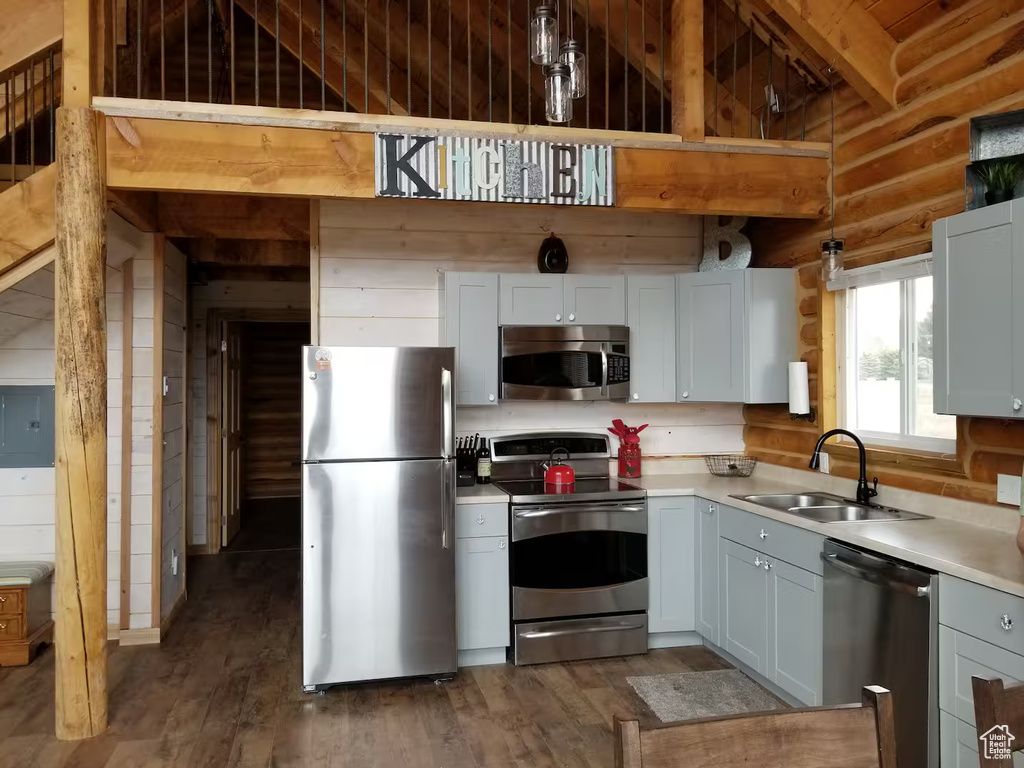 Kitchen featuring light countertops, appliances with stainless steel finishes, a sink, and dark wood-type flooring