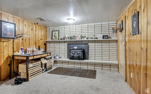 Miscellaneous room with wooden walls, a wood stove, visible vents, and carpet