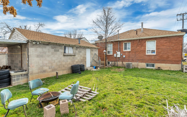 Rear view of house with an outdoor fire pit, a yard, and a shingled roof