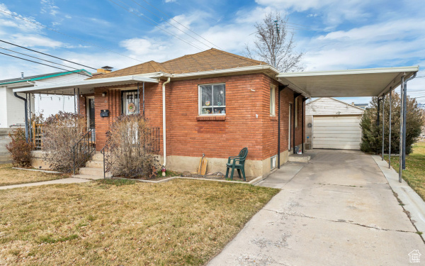 View of front of property with an outdoor structure, driveway, and a front yard
