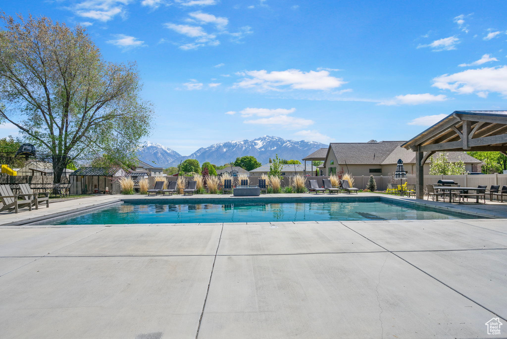 View of pool featuring a patio, a mountain view, and fence