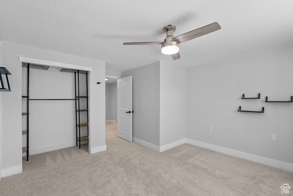 Unfurnished bedroom featuring a textured ceiling, carpet, baseboards, and a ceiling fan