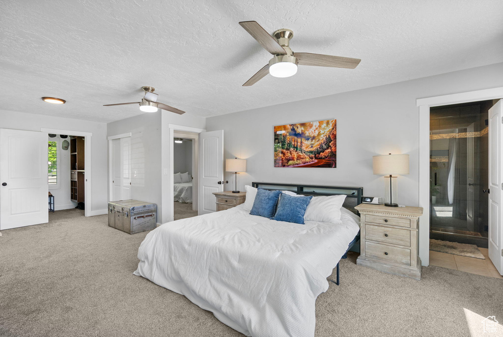 Bedroom with carpet, a textured ceiling, connected bathroom, and ceiling fan