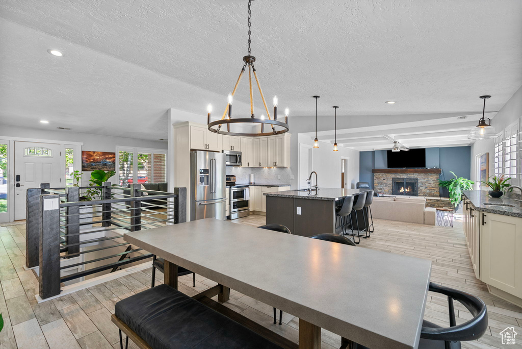 Dining area with light wood finished floors, a fireplace, a textured ceiling, a chandelier, and recessed lighting