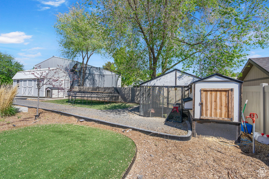View of yard featuring a storage shed, a trampoline, an outdoor structure, and fence
