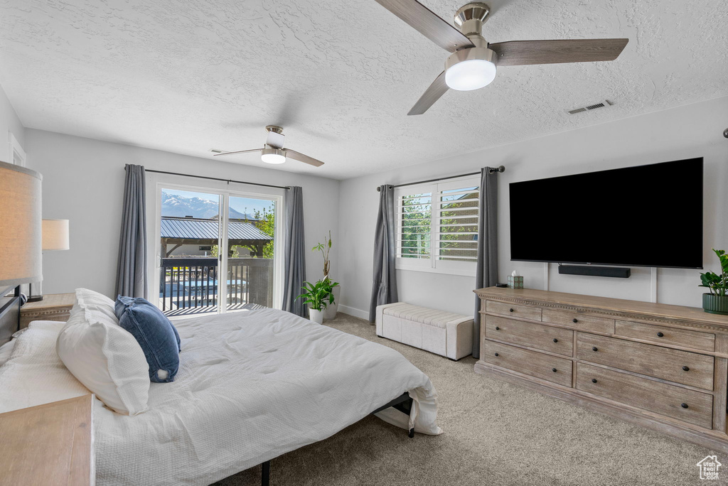 Bedroom featuring light colored carpet, a textured ceiling, visible vents, ceiling fan, and access to exterior