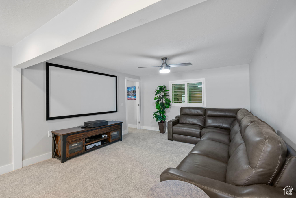 Carpeted cinema with ceiling fan and baseboards