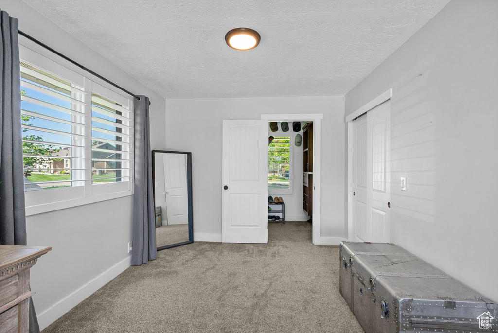 Unfurnished bedroom featuring a closet, a textured ceiling, baseboards, and carpet floors