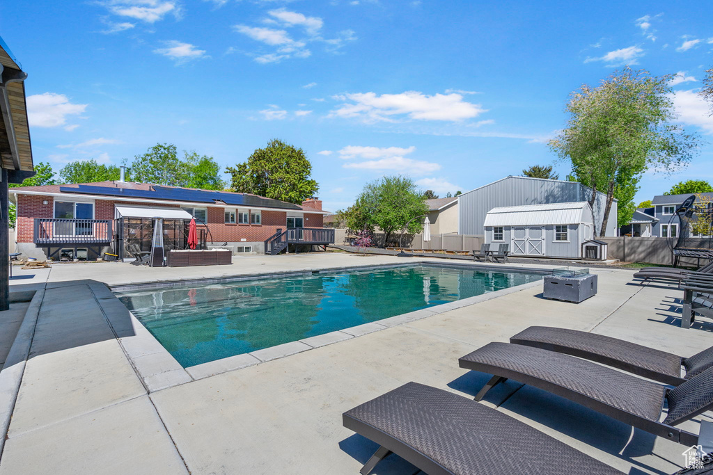 View of swimming pool with a patio, fence, a shed, an outbuilding, and a fenced in pool