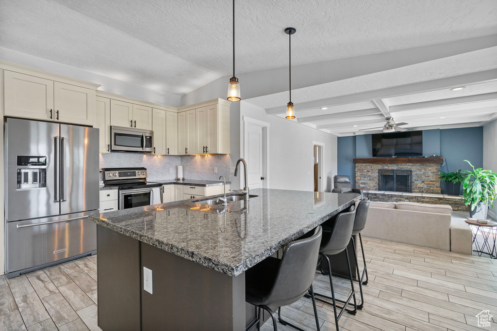 Kitchen with a ceiling fan, a sink, stainless steel appliances, light wood-type flooring, and cream cabinets