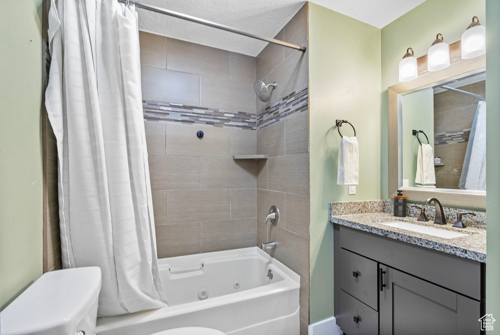 Full bath featuring toilet, vanity, and a combined bath / shower with jetted tub