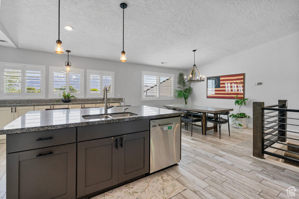 Kitchen featuring a sink, a textured ceiling, a notable chandelier, and dishwasher