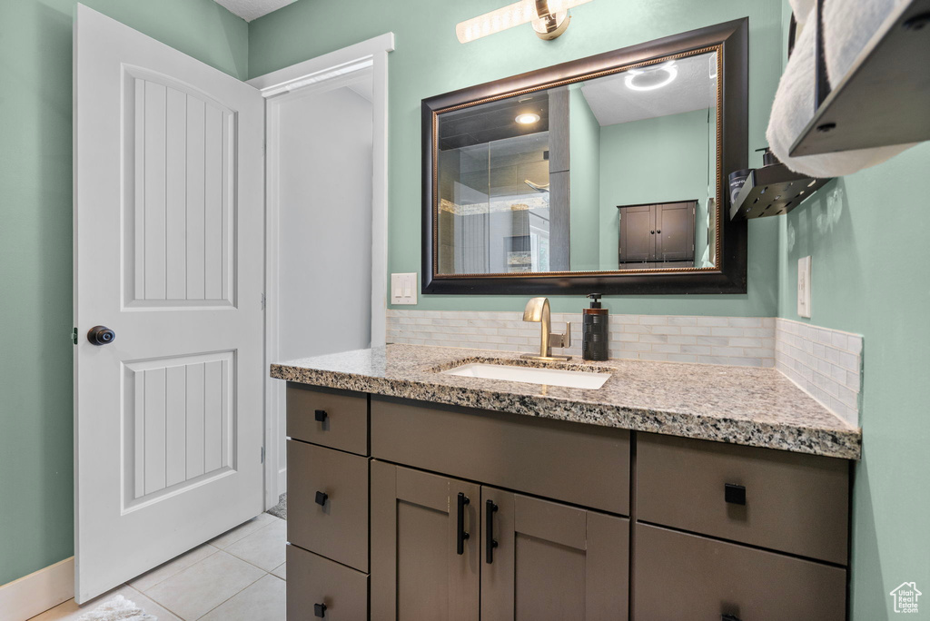 Bathroom with decorative backsplash, tile patterned flooring, and vanity