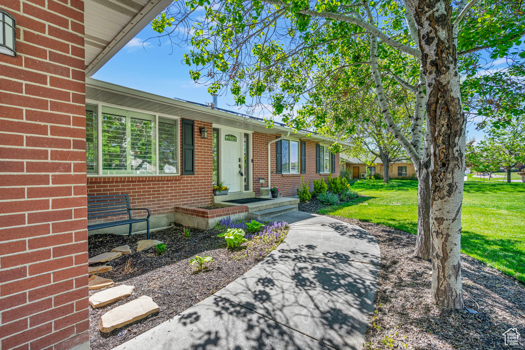 Doorway to property with a lawn and brick siding