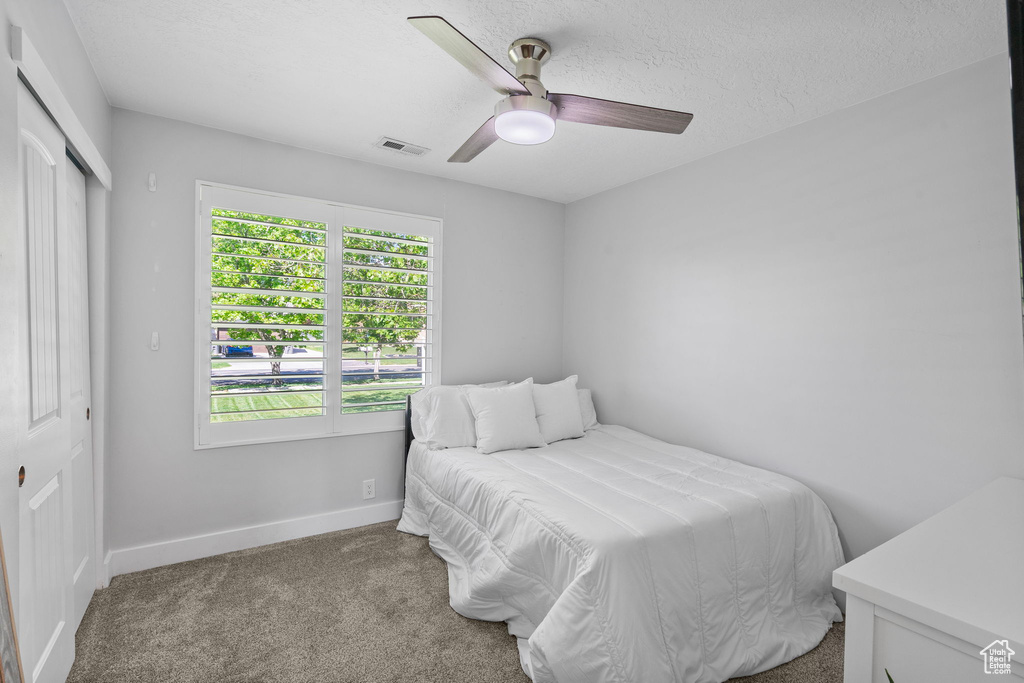 Carpeted bedroom featuring baseboards, ceiling fan, a closet, and visible vents