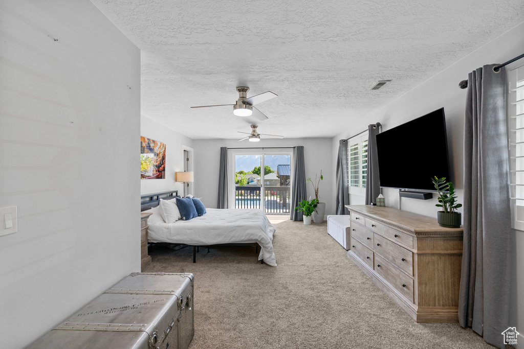 Carpeted bedroom with a textured ceiling, access to outside, a ceiling fan, and visible vents