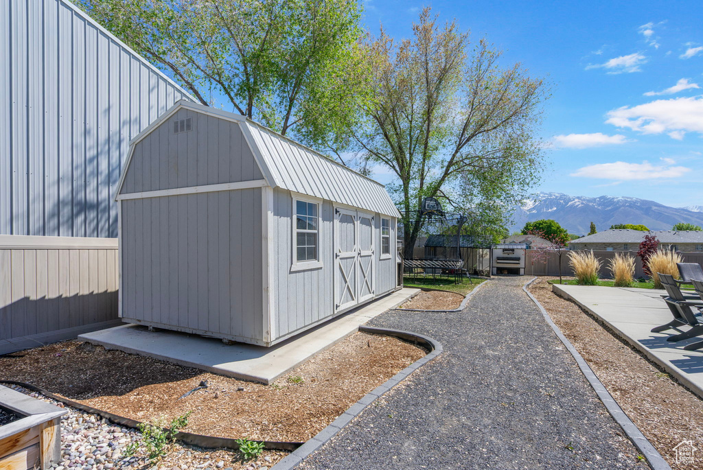 View of home's exterior featuring a patio area, a mountain view, a storage unit, an outbuilding, and a fenced backyard