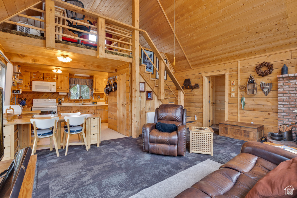 Living area with wooden ceiling, wooden walls, and dark carpet