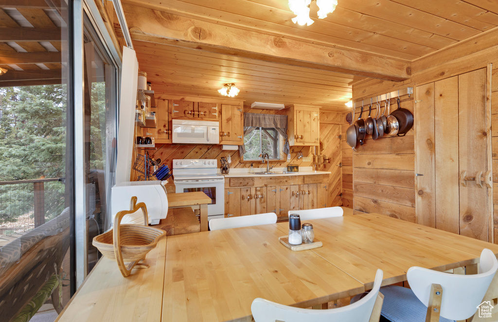 Dining room featuring beamed ceiling, wooden walls, and wood ceiling