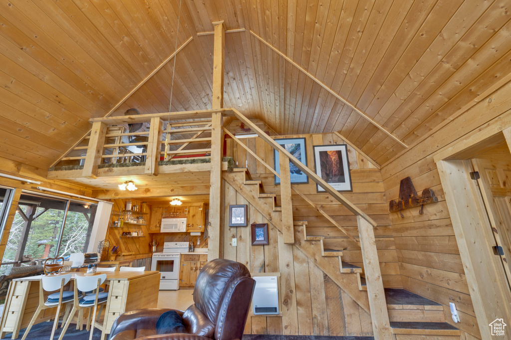 Living area with wooden ceiling, wooden walls, stairs, and high vaulted ceiling