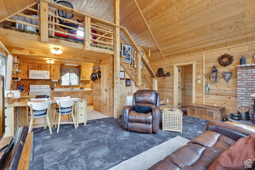 Living area featuring wooden ceiling, wood walls, stairs, and carpet floors