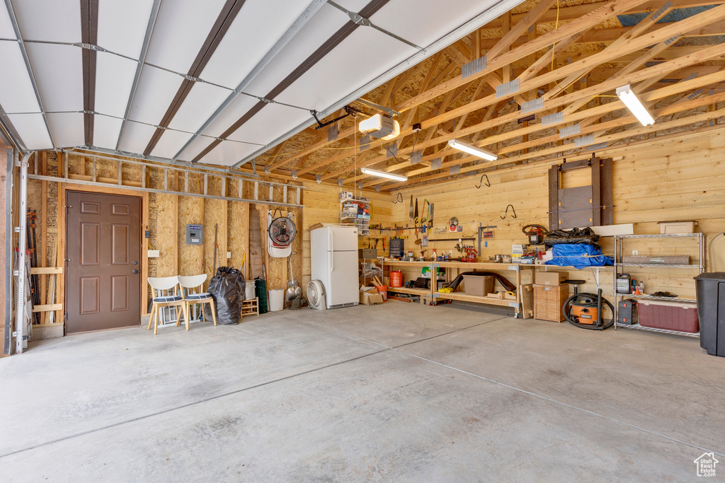 Garage featuring freestanding refrigerator, a workshop area, and a garage door opener