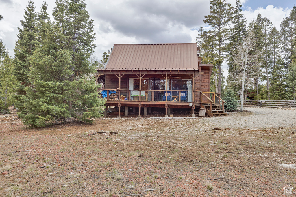 Rear view of house featuring a deck, metal roof, and fence