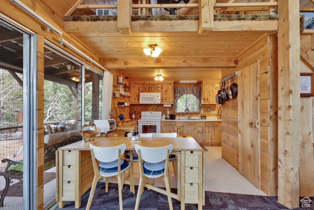 Dining space featuring a wealth of natural light, wooden walls, a toaster, and wood ceiling