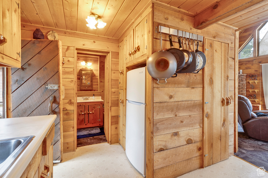Interior space with freestanding refrigerator, light floors, wood walls, and wooden ceiling