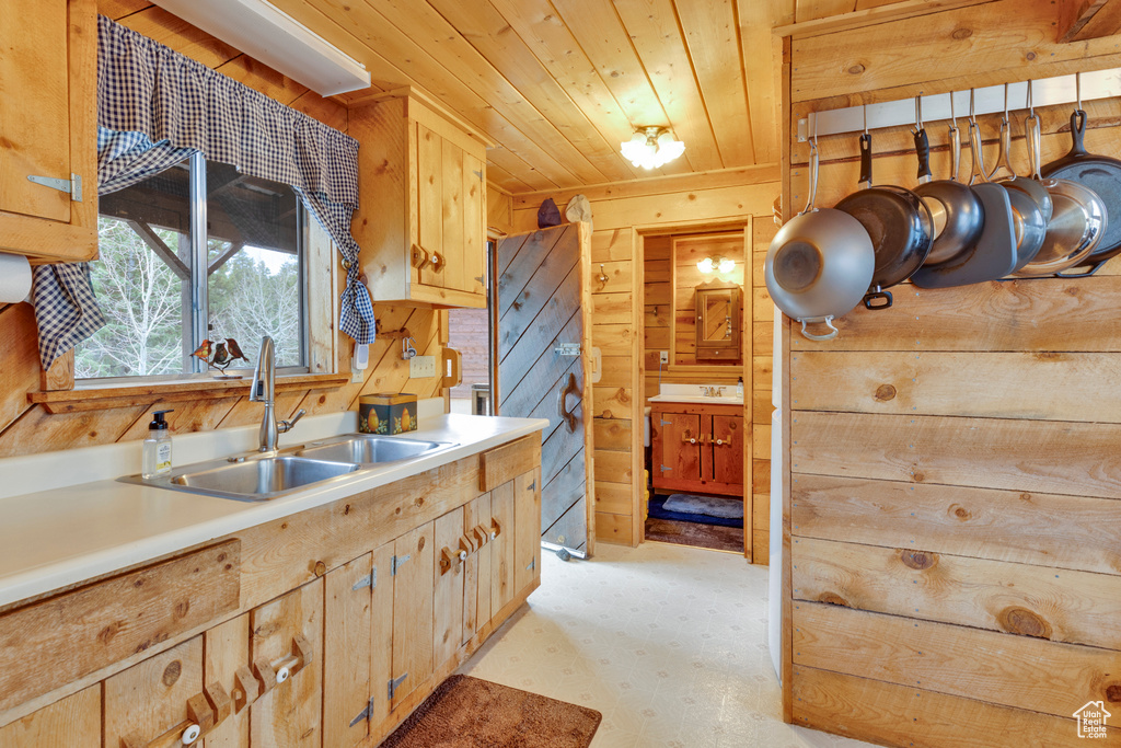 Kitchen with light floors, wood ceiling, a sink, wood walls, and light countertops