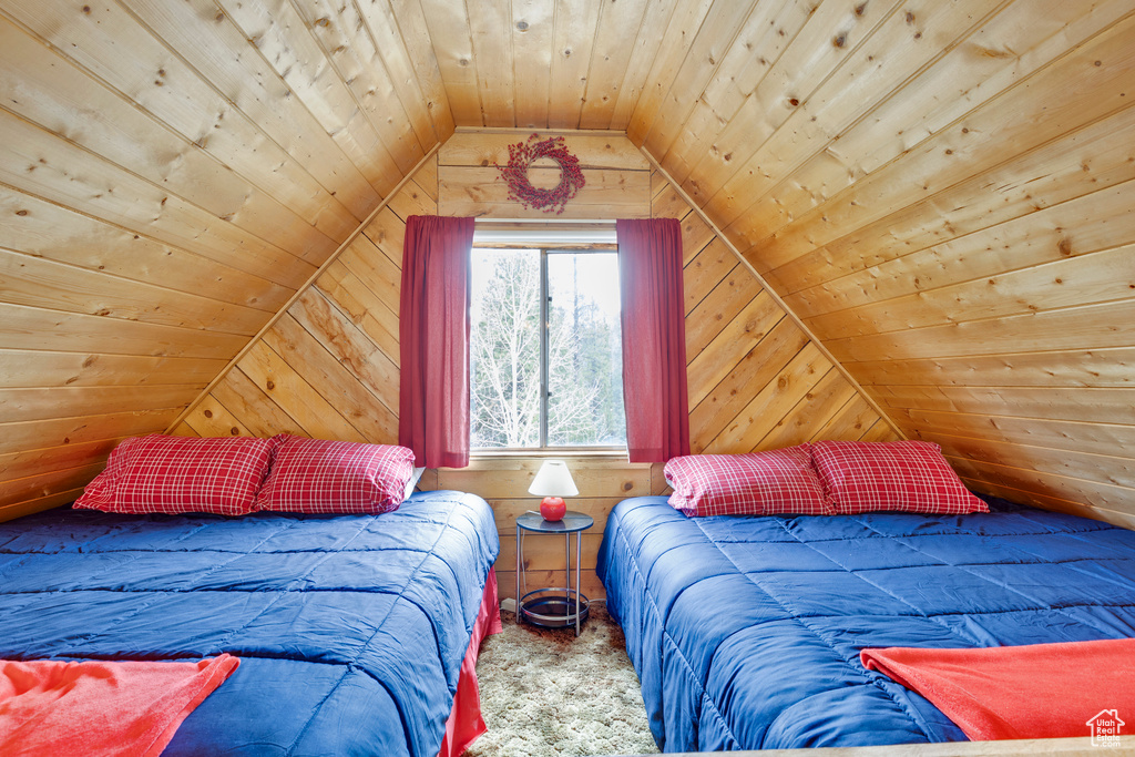 Carpeted bedroom featuring wood walls, wooden ceiling, and vaulted ceiling