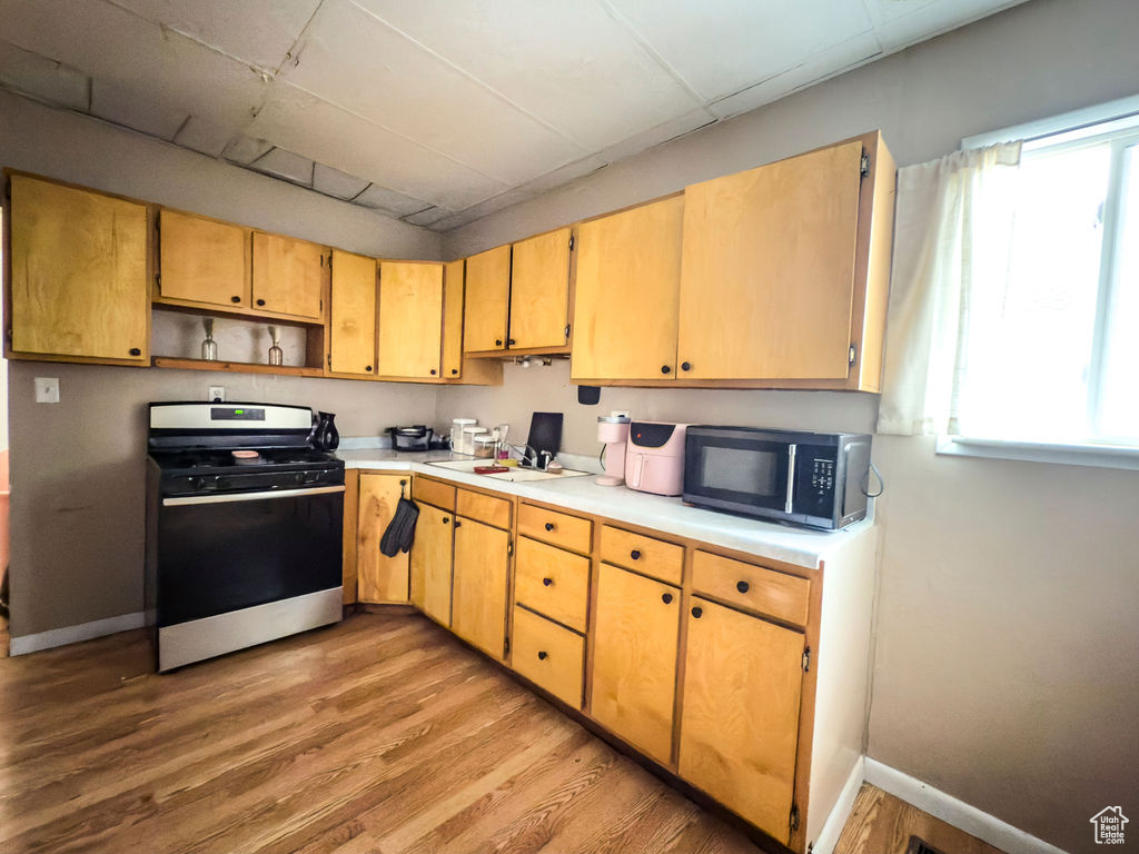 Kitchen featuring stainless steel gas range oven, light countertops, plenty of natural light, and light wood-style floors