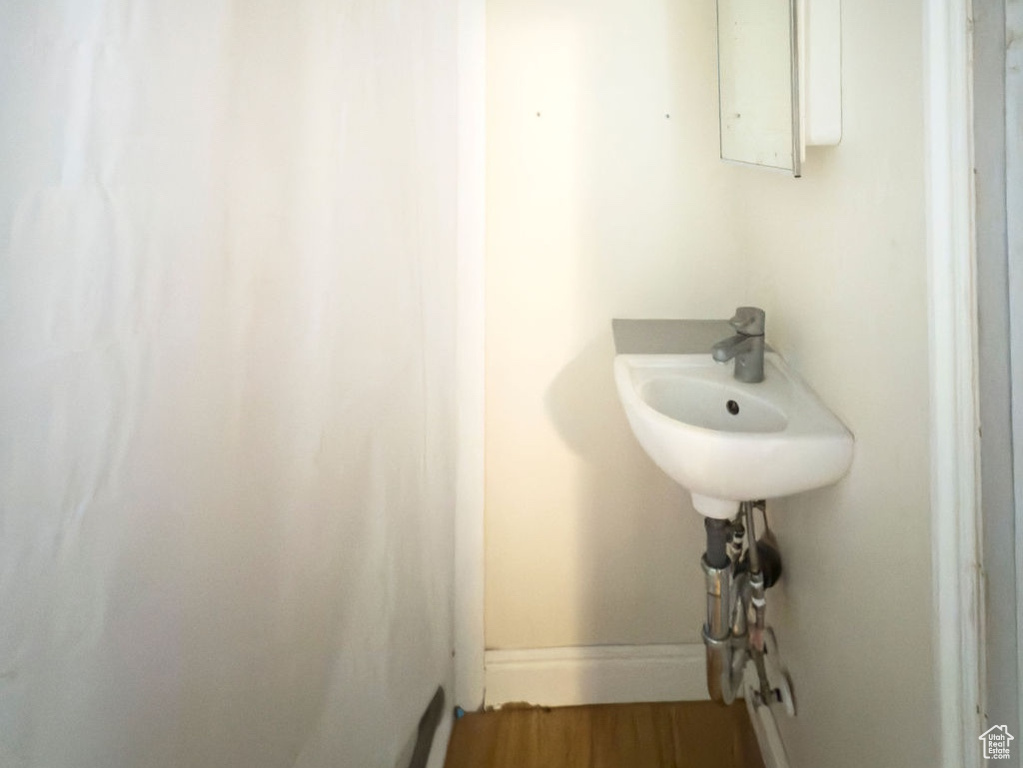 Bathroom featuring baseboards, a sink, and wood finished floors