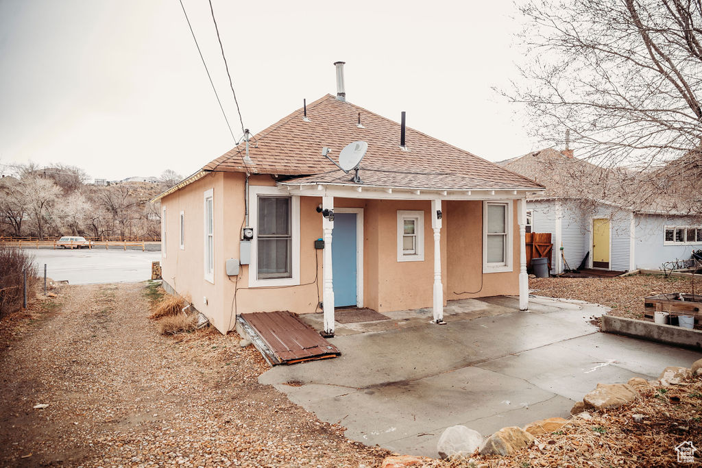 Rear view of house featuring stucco siding and roof with shingles