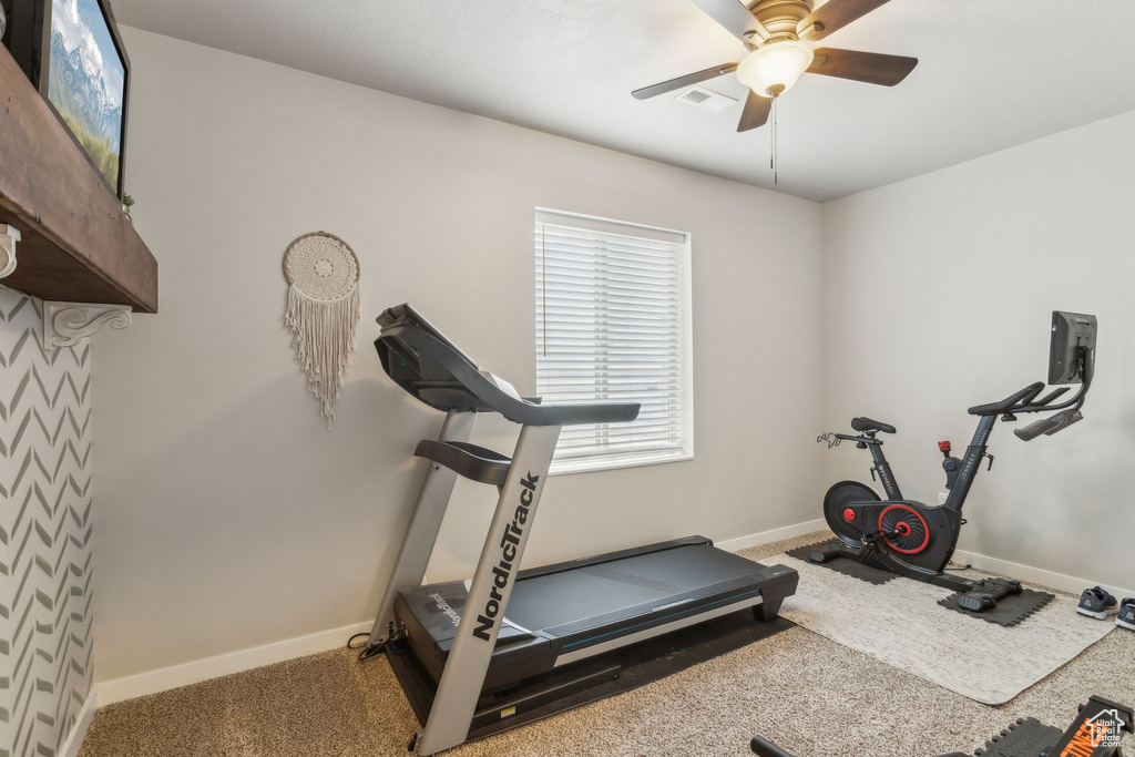Exercise area featuring baseboards, carpet floors, visible vents, and a ceiling fan