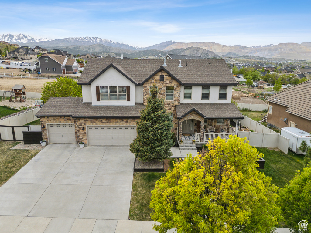 View of front of home with a mountain view, stucco siding, stone siding, and a shingled roof