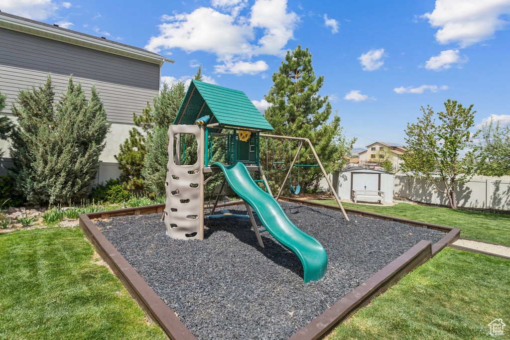 View of play area with a storage shed, an outbuilding, fence, and a lawn
