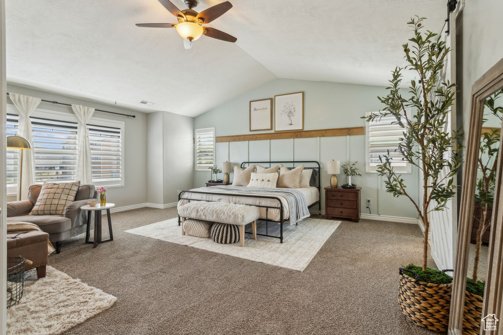 Carpeted bedroom with ceiling fan, lofted ceiling, baseboards, and visible vents