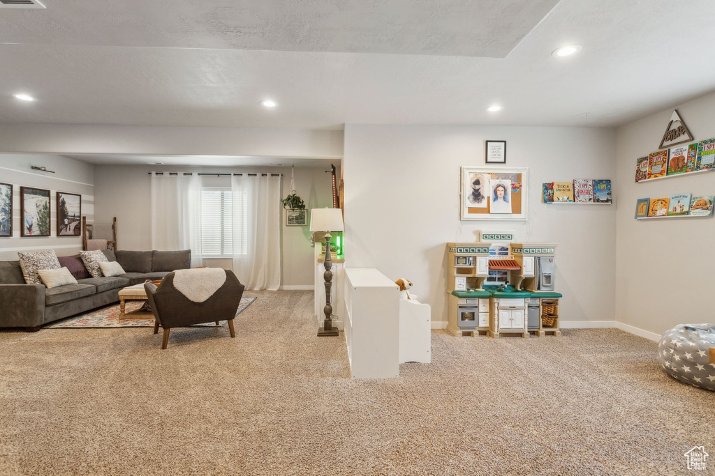 Carpeted living room with baseboards, visible vents, and recessed lighting