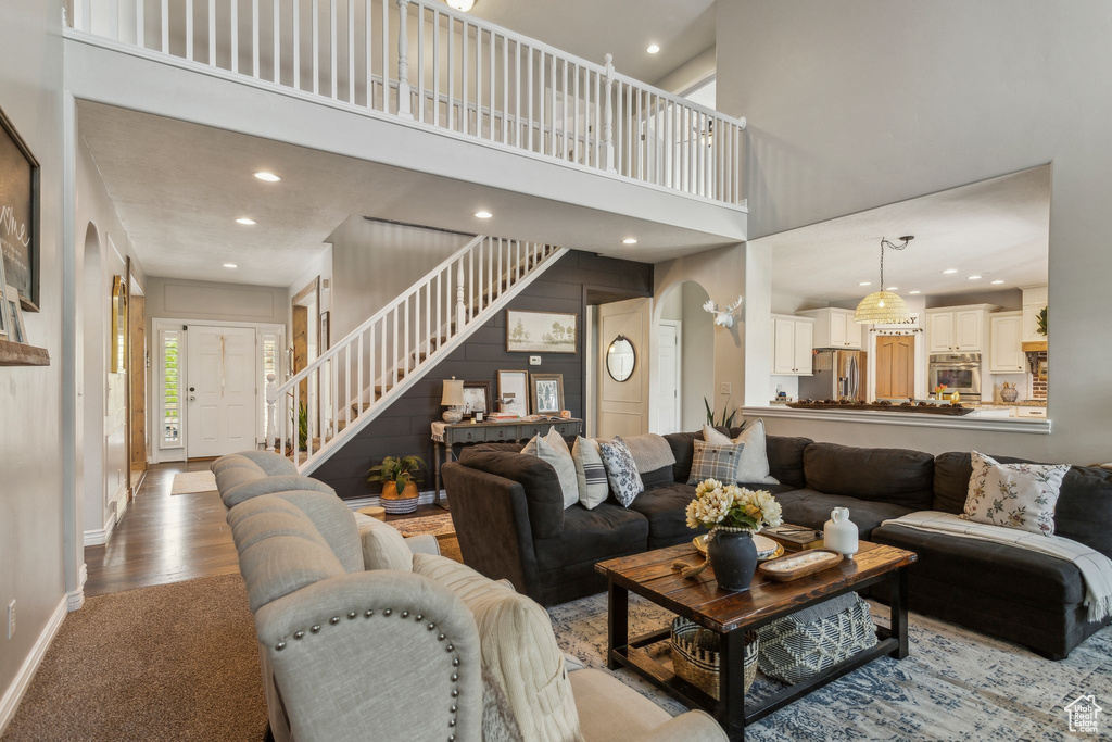 Living area with stairs, baseboards, a towering ceiling, and recessed lighting