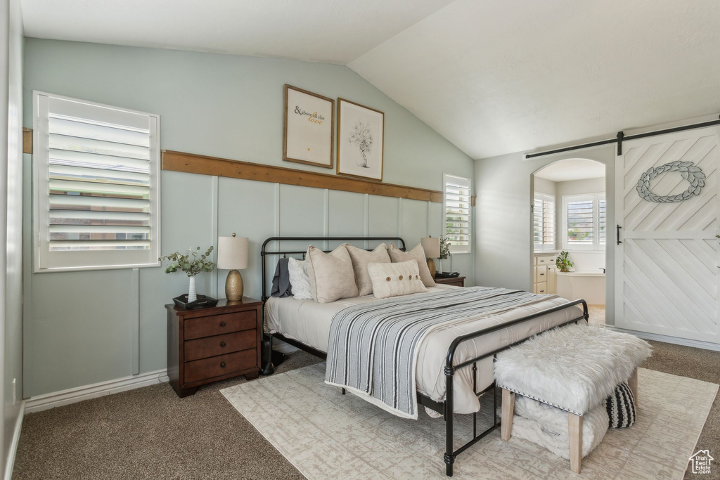 Bedroom with lofted ceiling, ensuite bath, a barn door, and carpet floors