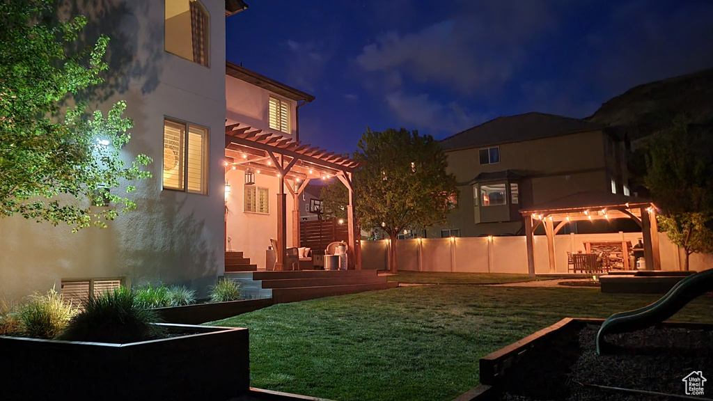 Yard at twilight with a pergola, a gazebo, fence, and a patio area