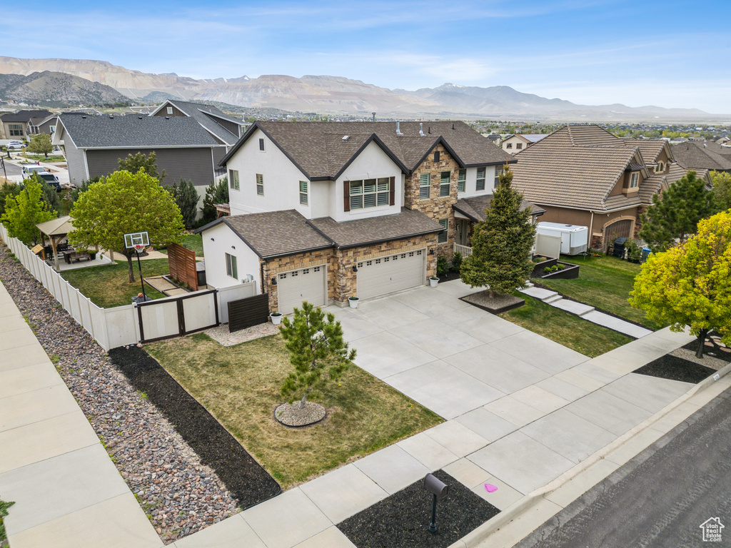 Traditional-style home with fence, stone siding, a residential view, a garage, and stucco siding