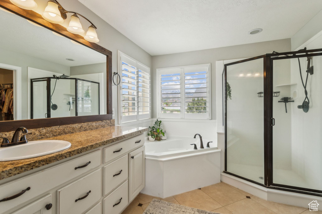 Full bath with a garden tub, a stall shower, a walk in closet, tile patterned flooring, and vanity