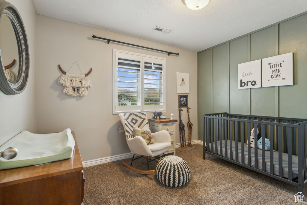 Bedroom with baseboards, a nursery area, visible vents, and carpet floors