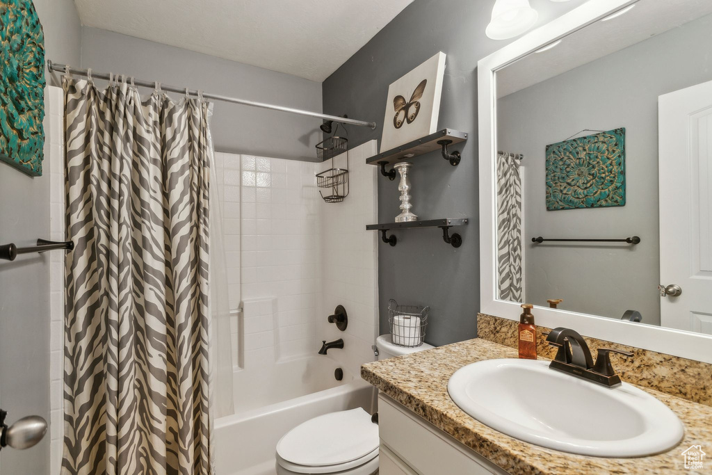 Full bathroom featuring toilet, vanity, and shower / bathtub combination with curtain