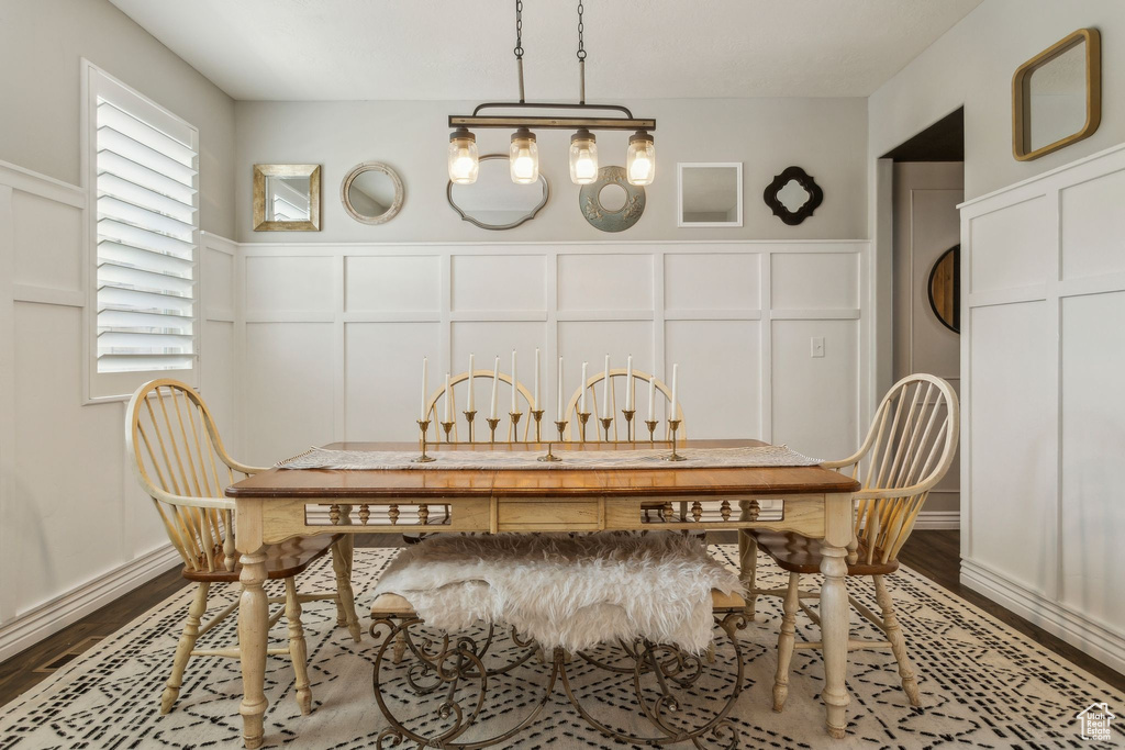 Dining space with a decorative wall, wainscoting, and wood finished floors