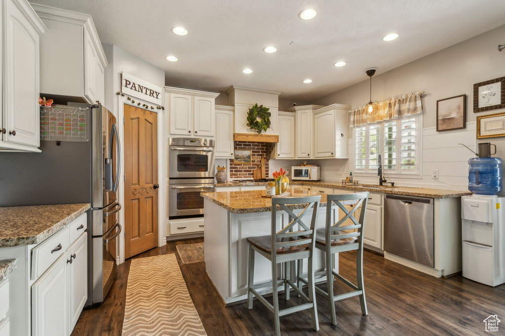 Kitchen featuring stone countertops, recessed lighting, a center island, decorative backsplash, and stainless steel appliances