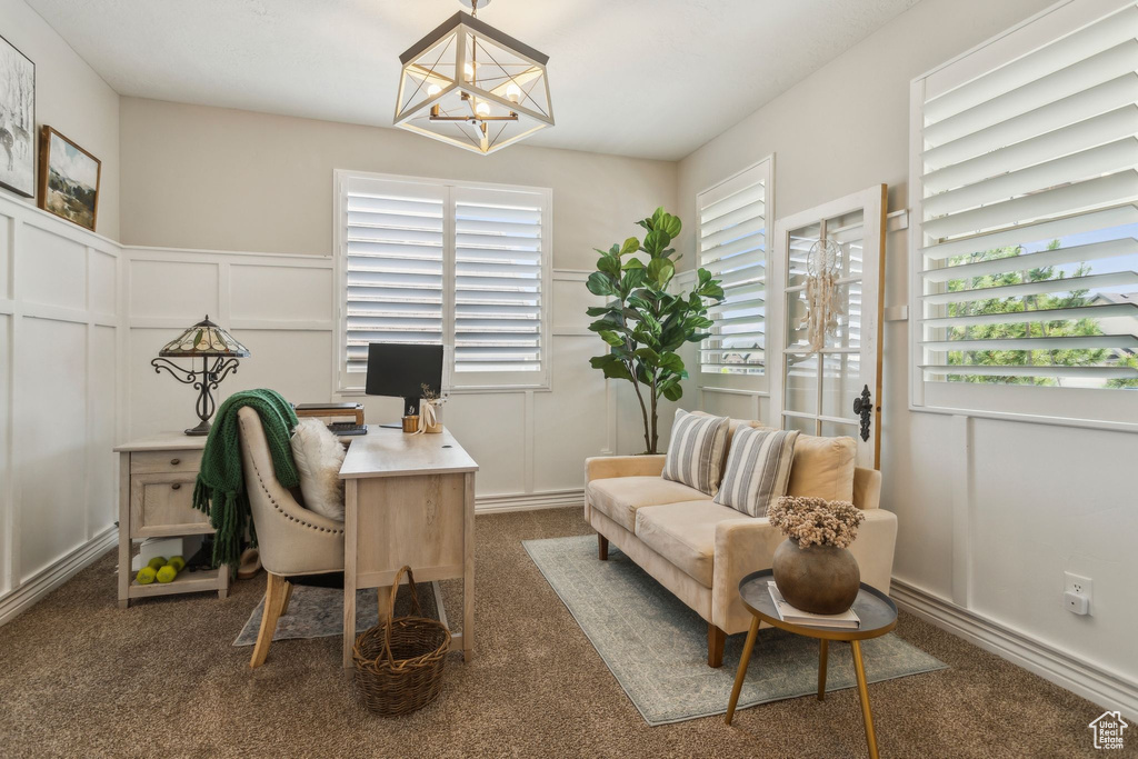 Carpeted office space with a decorative wall, a chandelier, and wainscoting